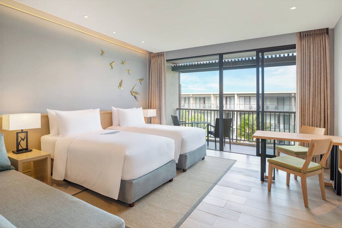 Hotelkamer met twee bedden, een balkon, een eettafel en uitzicht.