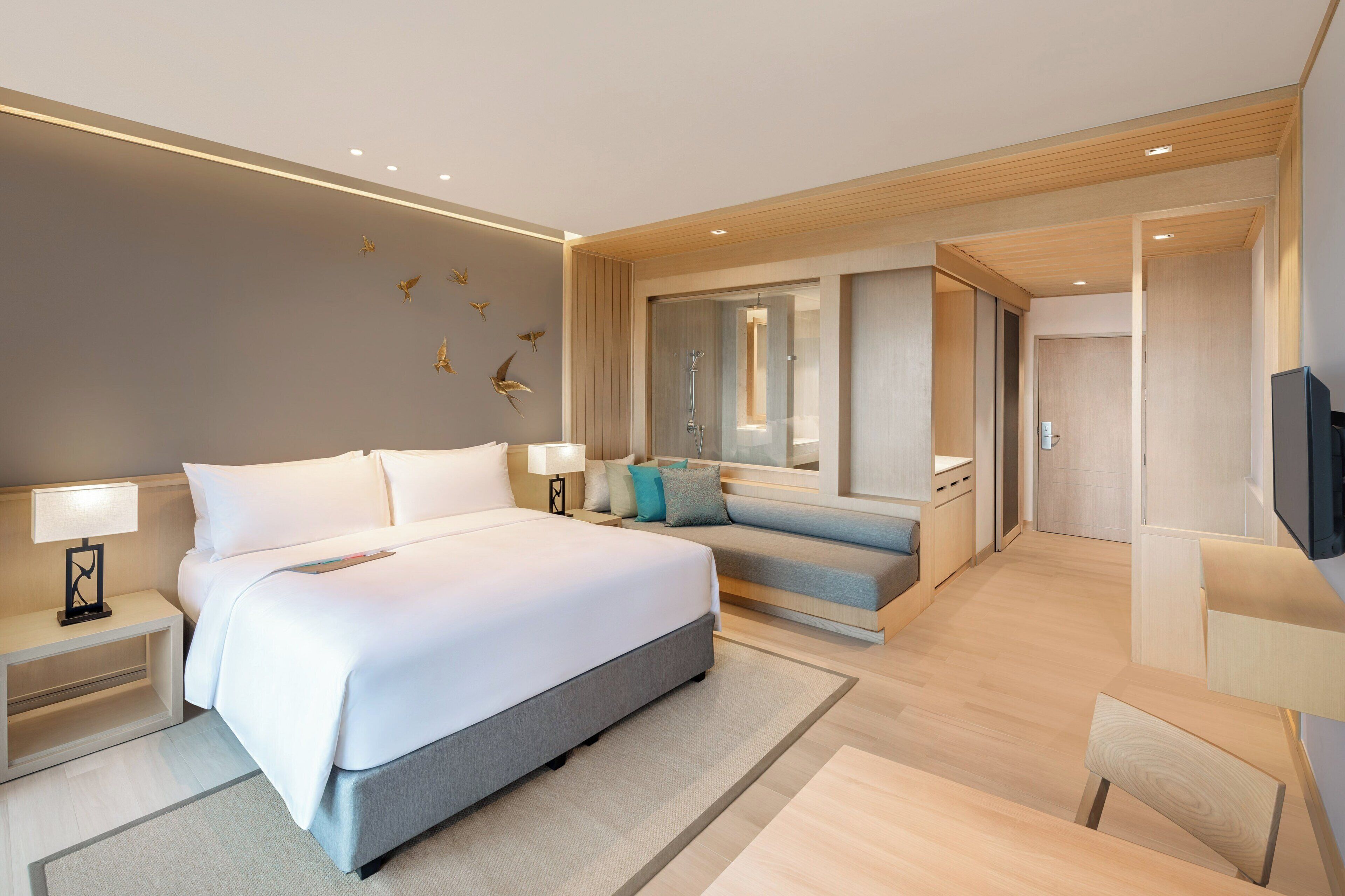 Een moderne hotelkamer met een groot bed, een zithoek, een televisie en een badkamer met douche.