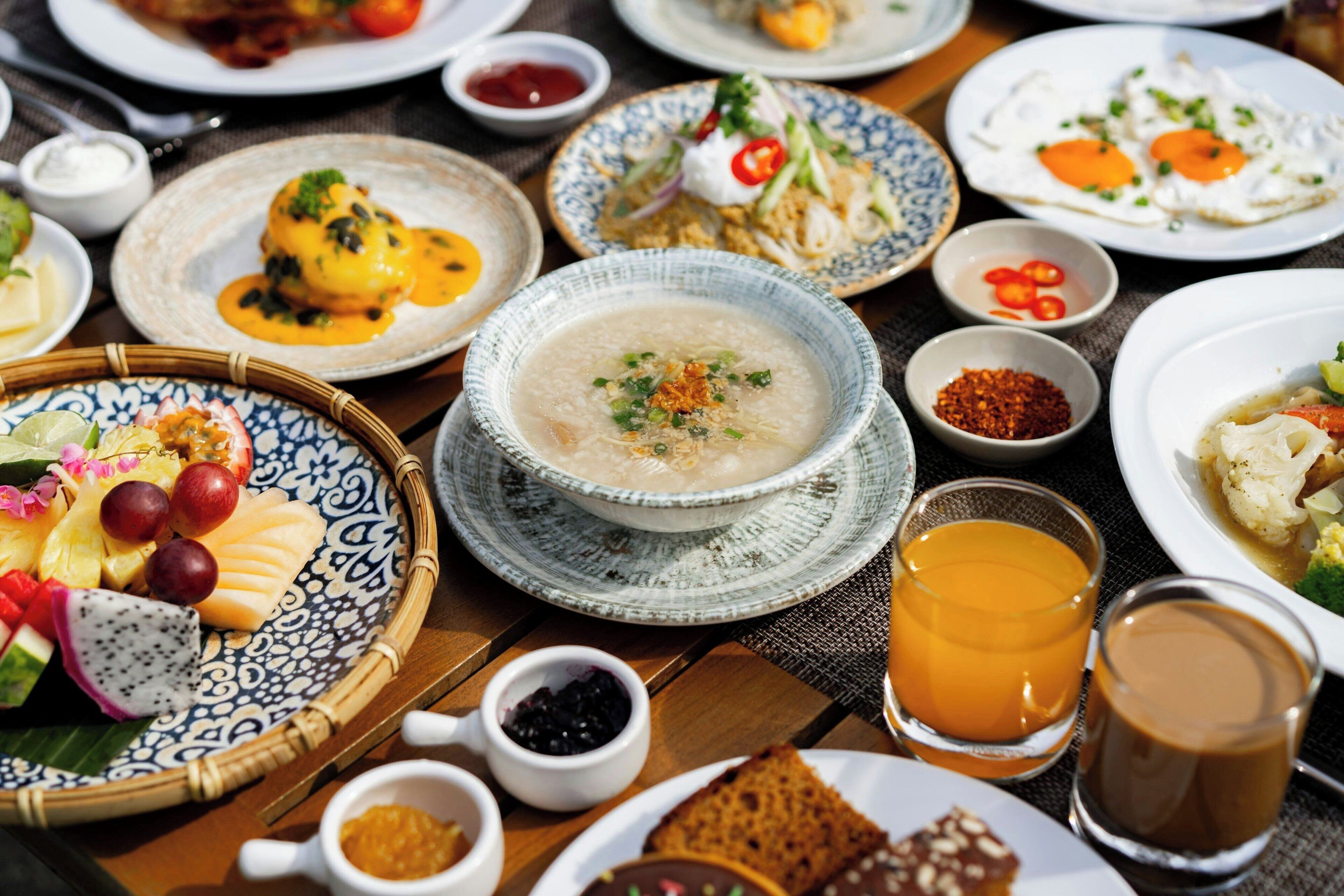 A variety of dishes on a table, including a bowl of soup, plates with eggs, and a plate with a salad.