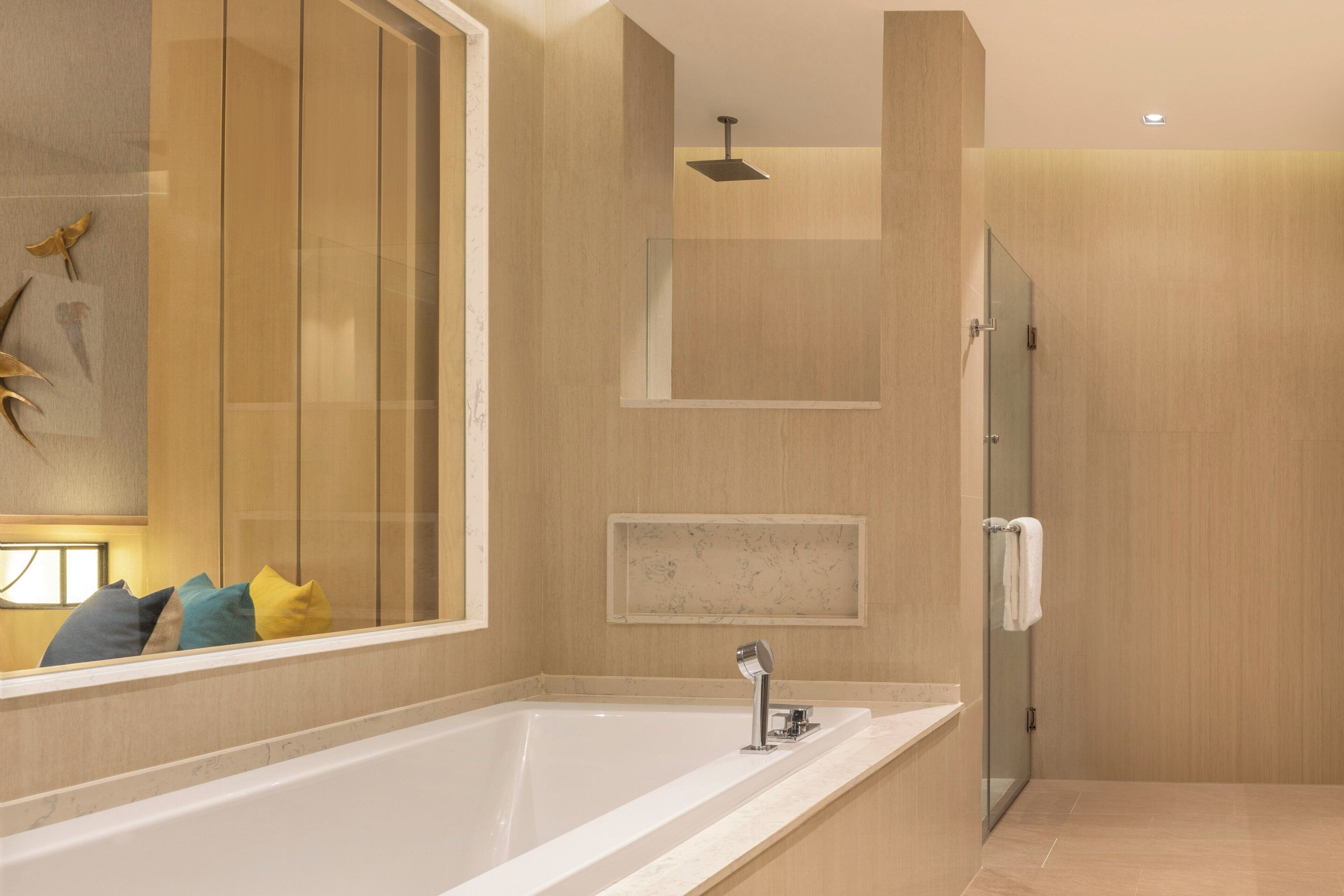 Ein modernes Badezimmer mit einer großen Badewanne, einer Duschkabine aus Glas und einem Spiegel mit dekorativen Elementen.