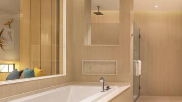 A modern bathroom with a large bathtub, a glass shower enclosure, and a mirror with decorative elements.