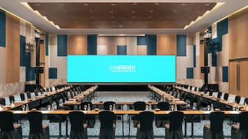 Uma sala de conferências com uma grande tela exibindo "Le Meridien Khao Lak Resort & Spa" na frente.