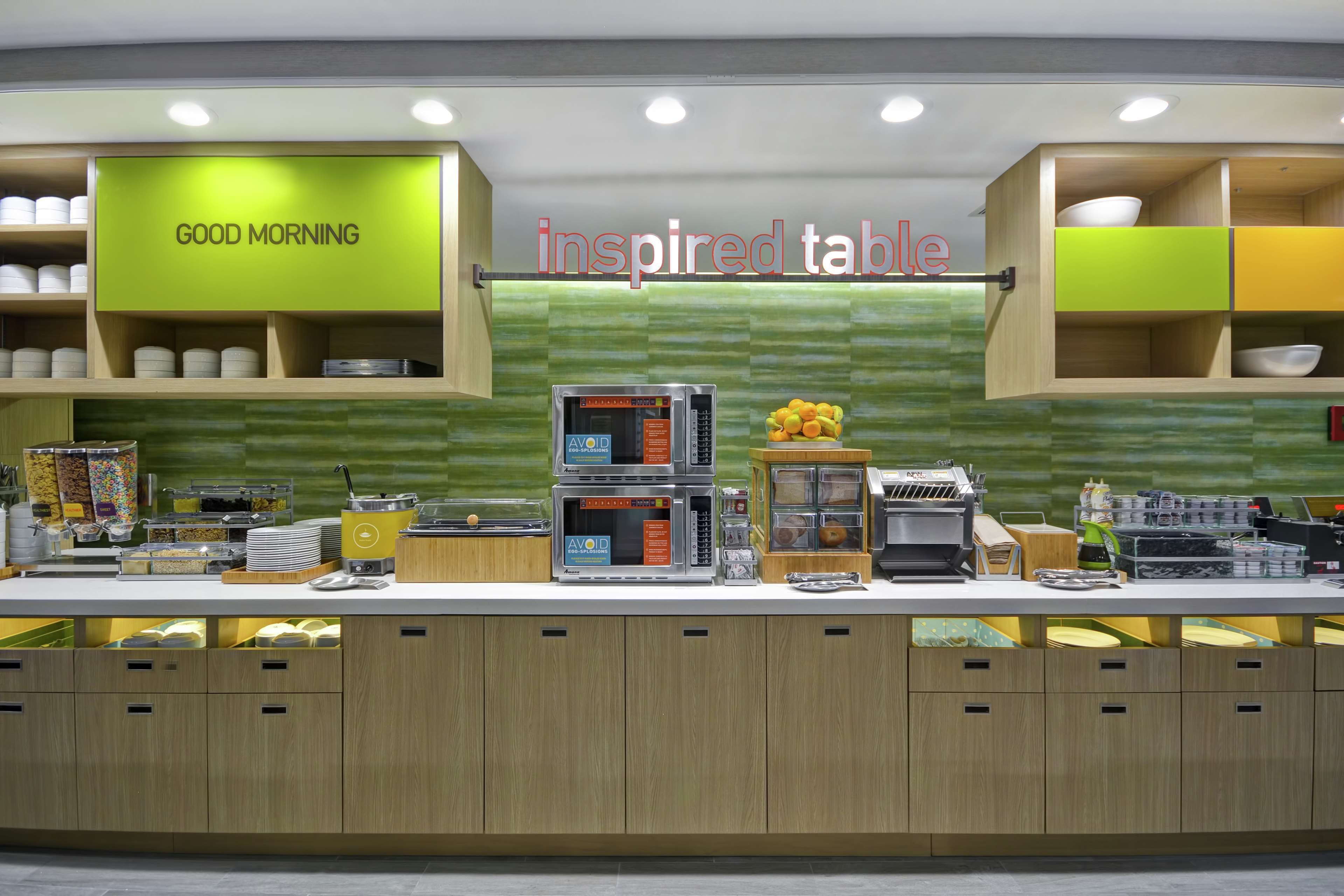 A breakfast bar with a 'GOOD MORNING' sign, a microwave, and various breakfast items.