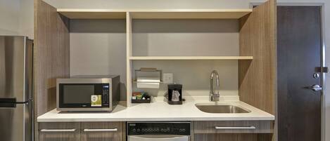 A compact kitchen with a microwave, coffee maker, dishwasher, and a sink.