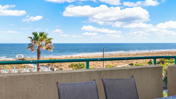 Un balcon avec vue sur la plage et l’océan.