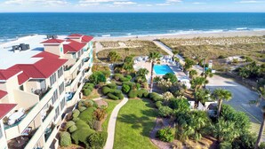 Un complexe hôtelier doté d’une piscine, situé en bord de mer et comprenant un bâtiment avec des balcons.