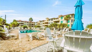Un espace aménagé au bord de la piscine, avec des chaises longues et un parasol bleu.