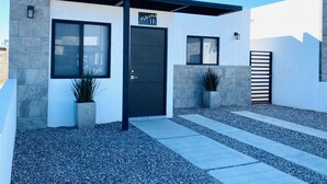 A modern building with a black door, a sign reading "Moana 11", and potted plants.
