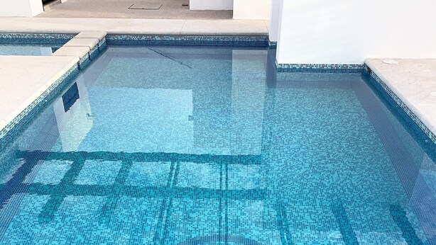 A clear view of a swimming pool with a tiled floor and a visible drain.