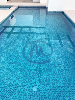 A clear view of a swimming pool with a tiled floor and a visible drain.
