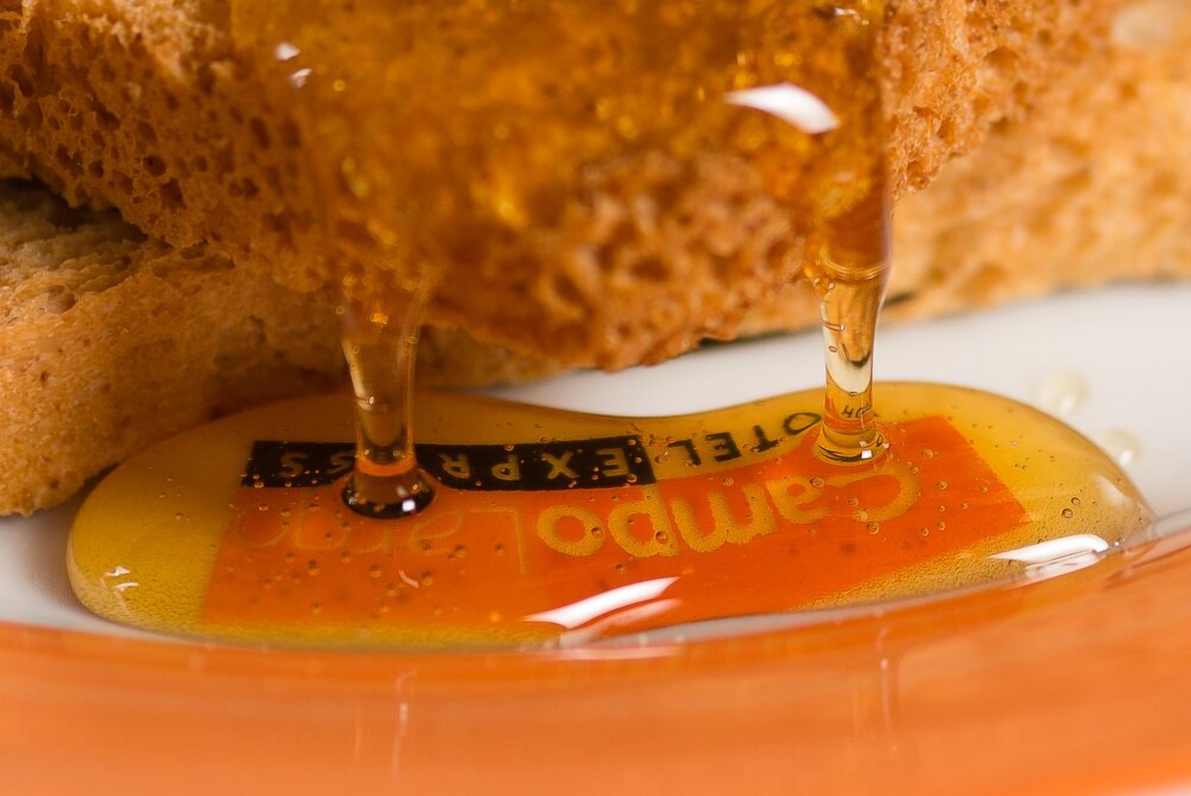 A close-up of a slice of bread with honey being poured onto it.