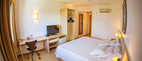A hotel room with a bed, desk, chair, and a TV.