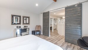 Un dormitorio moderno con una cama grande, un aparador y dos obras de arte enmarcadas en la pared.