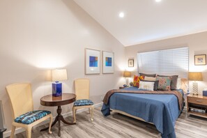 A bedroom with a bed, two chairs, a small table, and a nightstand. - Gorgeous Vineyard Views, Large private home w/heated Pool & Hot Tub included! (Glen Ellen)