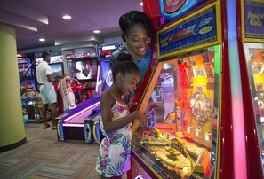 A gaming arcade with various machines, including a claw machine and a basketball game. - Oceanfront Suite at Family Friendly Resort + Official On-Site Rental Privileges (Myrtle Beach)