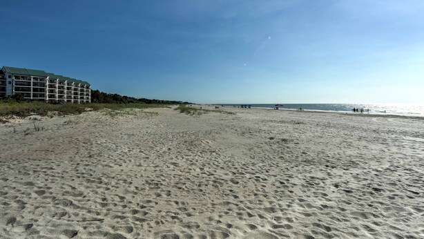 Uma praia com um prédio à esquerda.