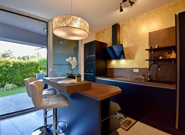 A modern kitchen with a bar area, a large window, and a view of the outdoors.