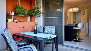 A modern dining area with a table and chairs, a hanging plant, and a view through a sliding door. - Amazing luxury apartment 200 m from the beach (Pula)