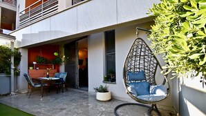 A patio with a dining table and chairs, a hanging chair, and potted plants. - Amazing luxury apartment 200 m from the beach (Pula)