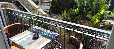 A balcony with a chessboard table, two wooden chairs, and a metal railing.