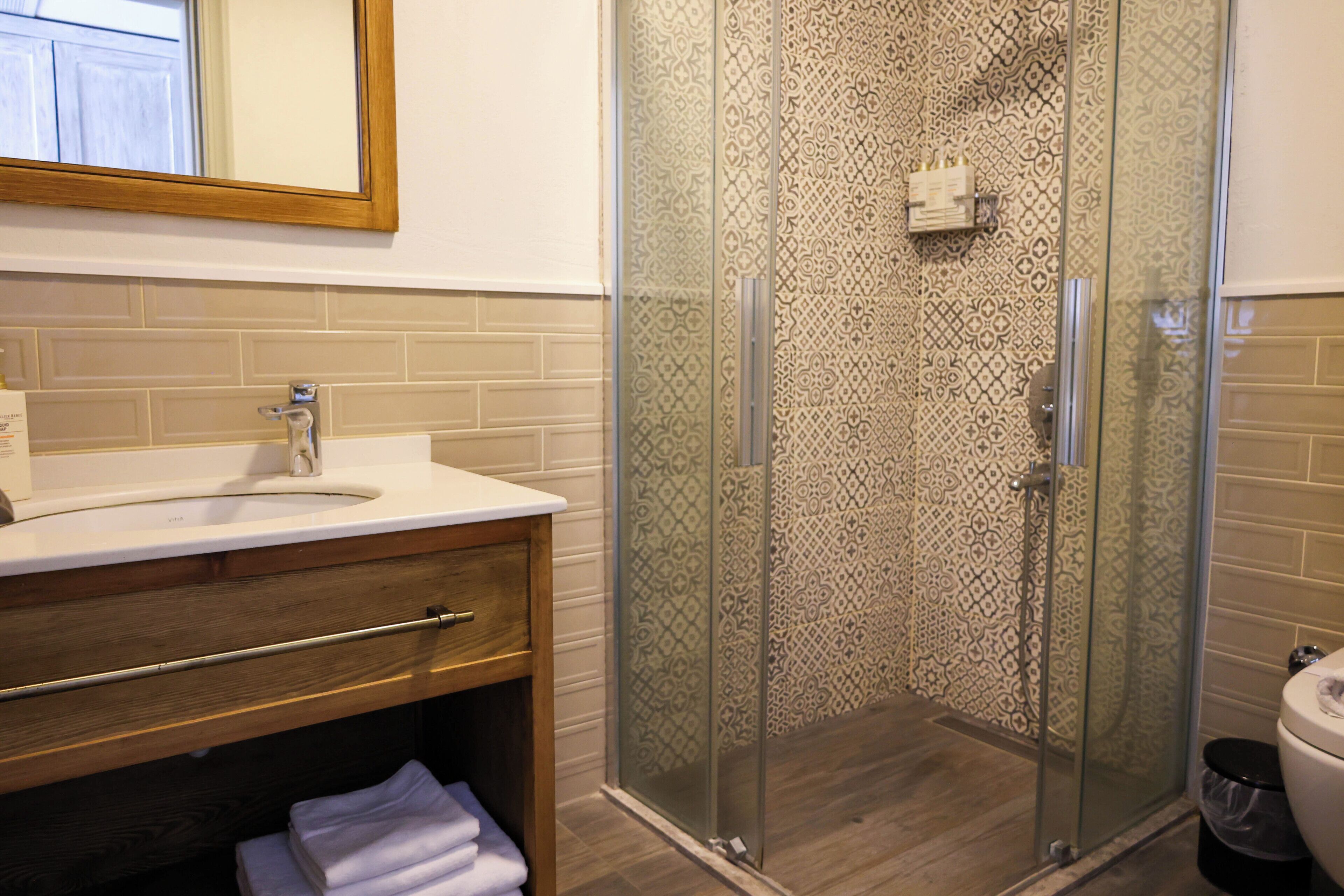 Une salle de bain avec un meuble-lavabo en bois, une cabine de douche en verre et des toilettes.