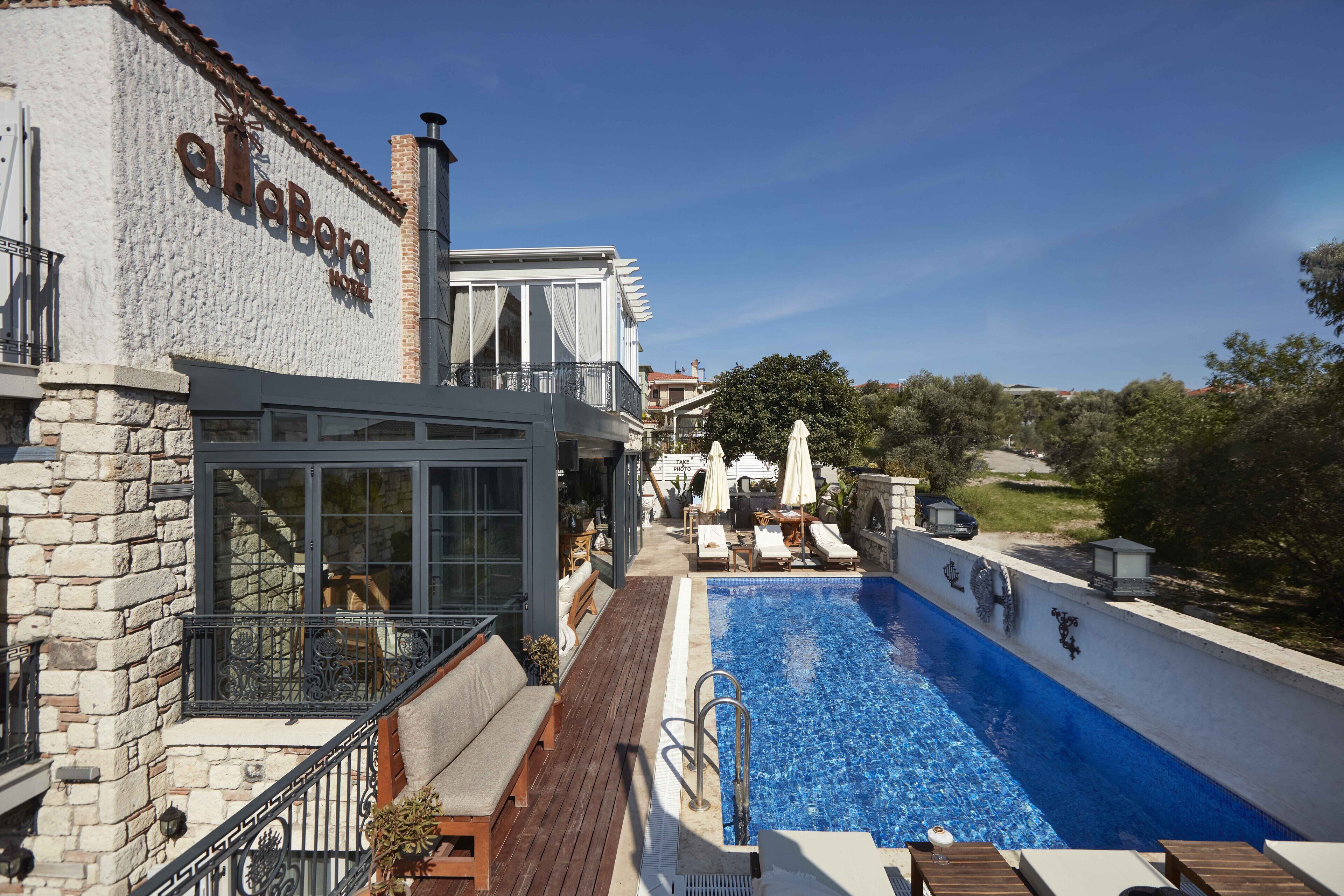 Un hotel con piscina, mobiliario exterior y fachada de piedra.