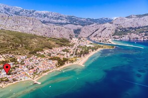 An aerial view of a coastal town with mountains in the background, a beach, and clear blue waters. - Villa with private heated pool, 50 meters from the sea. (Duće)