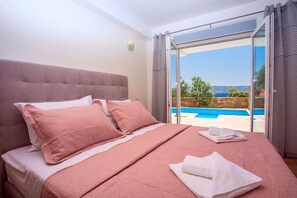 A bedroom with a large bed, a view of a pool, and a stone wall. - Villa with private heated pool, 50 meters from the sea. (Duće)