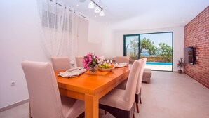 Uma área de refeições moderna com uma mesa de madeira, cadeiras bege e um vaso de flores.