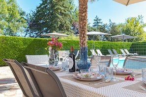 An outdoor dining area with a pool, chairs, and umbrellas. - Grauvière is a lovely holiday home (Anglars-Nozac)