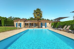 Piscina com espreguiçadeiras e uma palmeira.