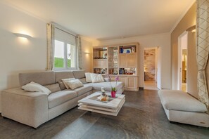 Uma sala de estar moderna com um sofá, mesa de centro e um armário de vidro.