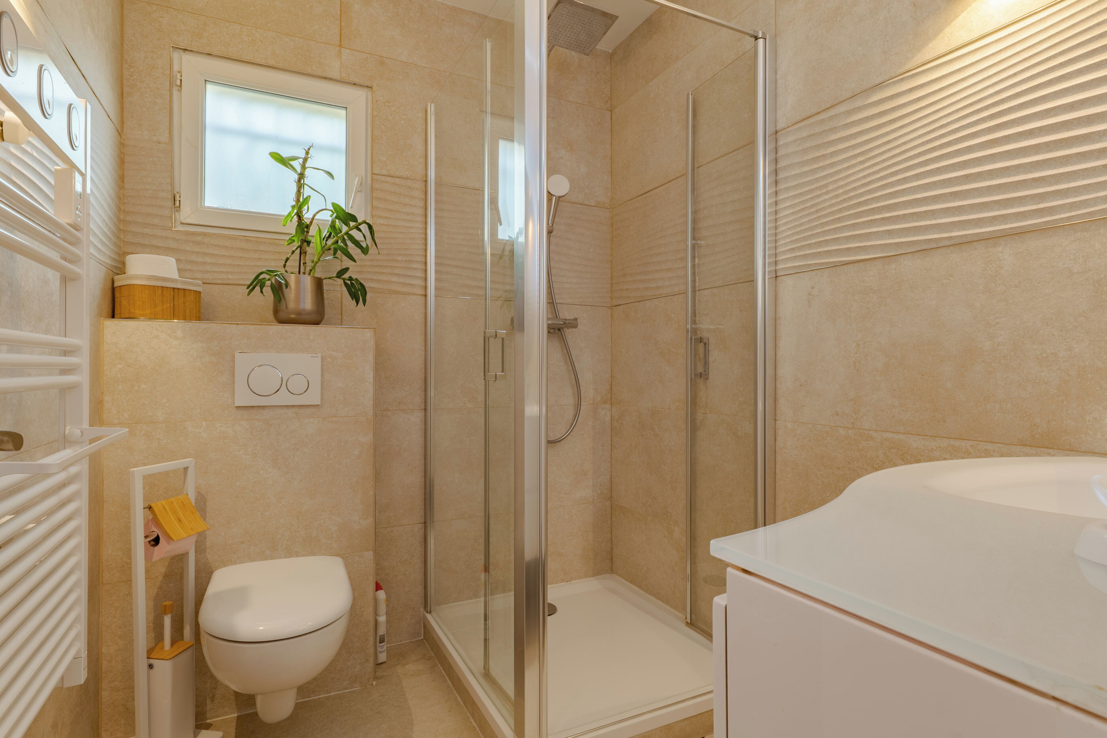 A modern bathroom with a glass-enclosed shower, a toilet, and a sink.