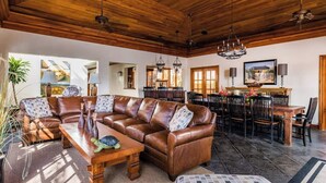 Ein geräumiges Wohnzimmer mit einer großen, braunen Ledersitzgruppe, einem Holztisch und einem Essbereich mit Tisch und Stühlen.