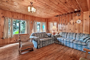 Un intérieur en bois avec un canapé, un fauteuil et un luminaire suspendu.