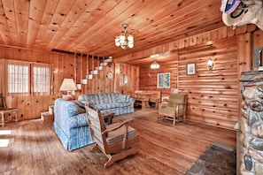 A log cabin interior with a sofa, a dining table, and a fireplace. - Vintage 1940s McCall Lakefront Cabin |Boat Slip (McCall)