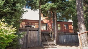 A rustic cabin with a wooden staircase leading to a porch. - Vintage 1940s McCall Lakefront Cabin |Boat Slip (McCall)