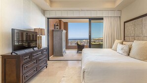 Una camera da letto con un letto grande, televisione, comò e vista sull'oceano.