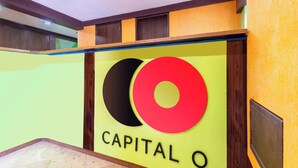 A reception area with a prominent sign reading "CAPITAL O" and a modern design with wooden accents and a yellow wall. - Capital O Df Inn, Ciudad de Mexico (Mexico City)