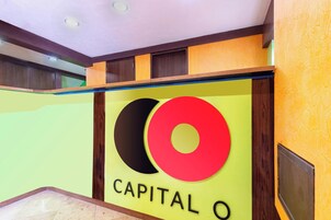 Un espace d'accueil avec une enseigne bien visible indiquant « CAPITAL O » et un design moderne agrémenté d'éléments en bois et d'un mur jaune.