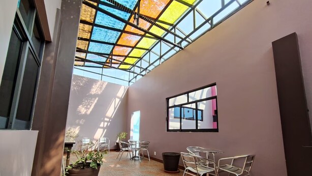 A spacious indoor area with a high ceiling, a glass roof, and a view of the sky. There are several chairs and tables arranged for seating. - Capital O Df Inn, Ciudad de Mexico (Mexico City)