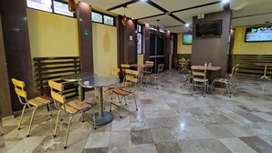A restaurant with a checkered floor, round tables, and wooden chairs. - Capital O Df Inn, Ciudad de Mexico (Mexico City)