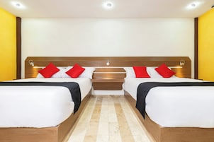Une chambre double avec deux lits, chacun doté d’une literie rouge et blanche, d’une tête de lit en bois et d’une petite table de chevet.