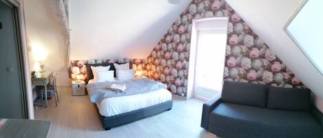 Ein Schlafzimmer mit einem Bett, einem Nachttisch, einem Sessel und einem Fenster.