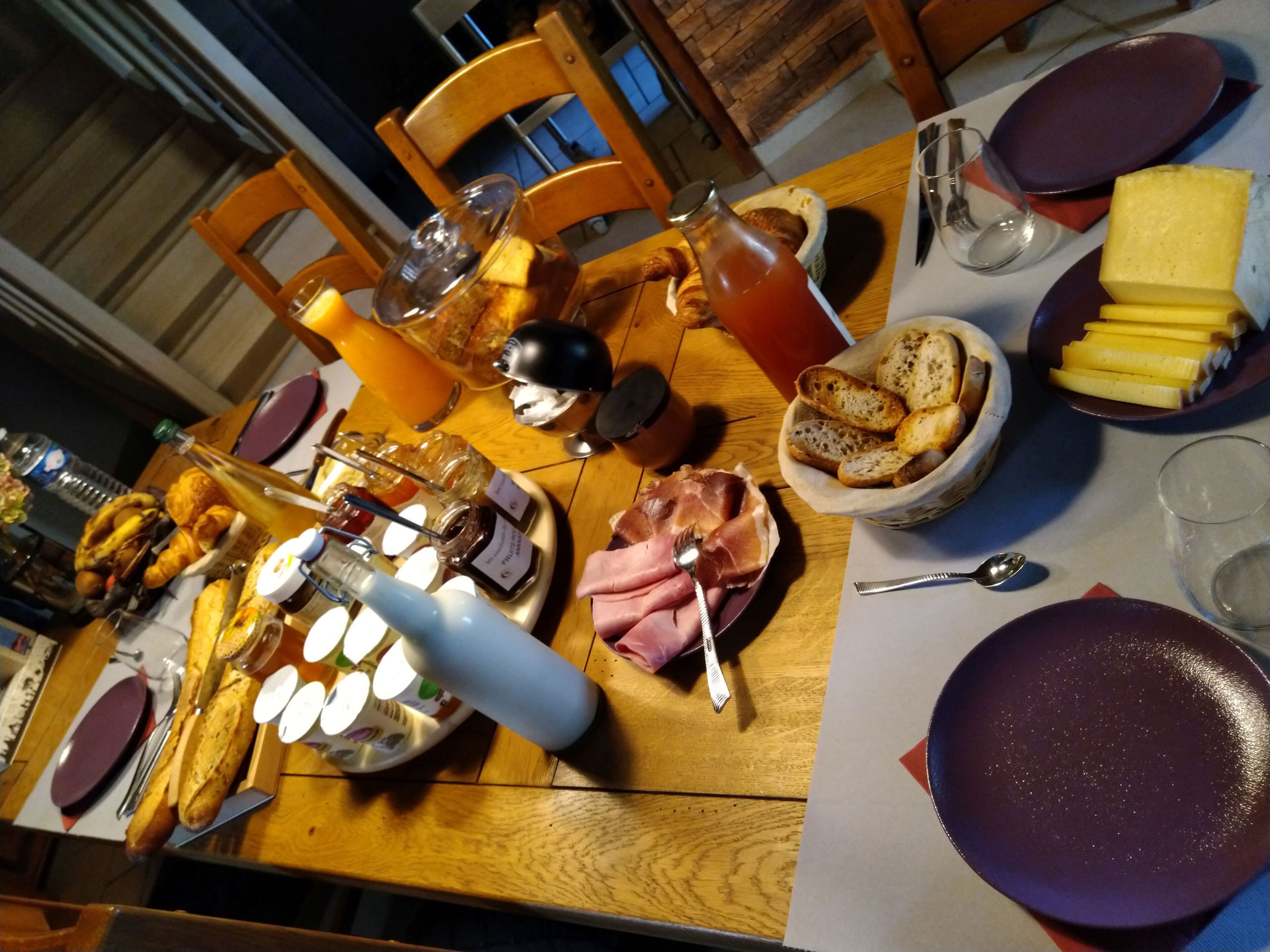 Een eettafel gedekt met diverse soorten eten, zoals brood, kaas en een fles wijn.