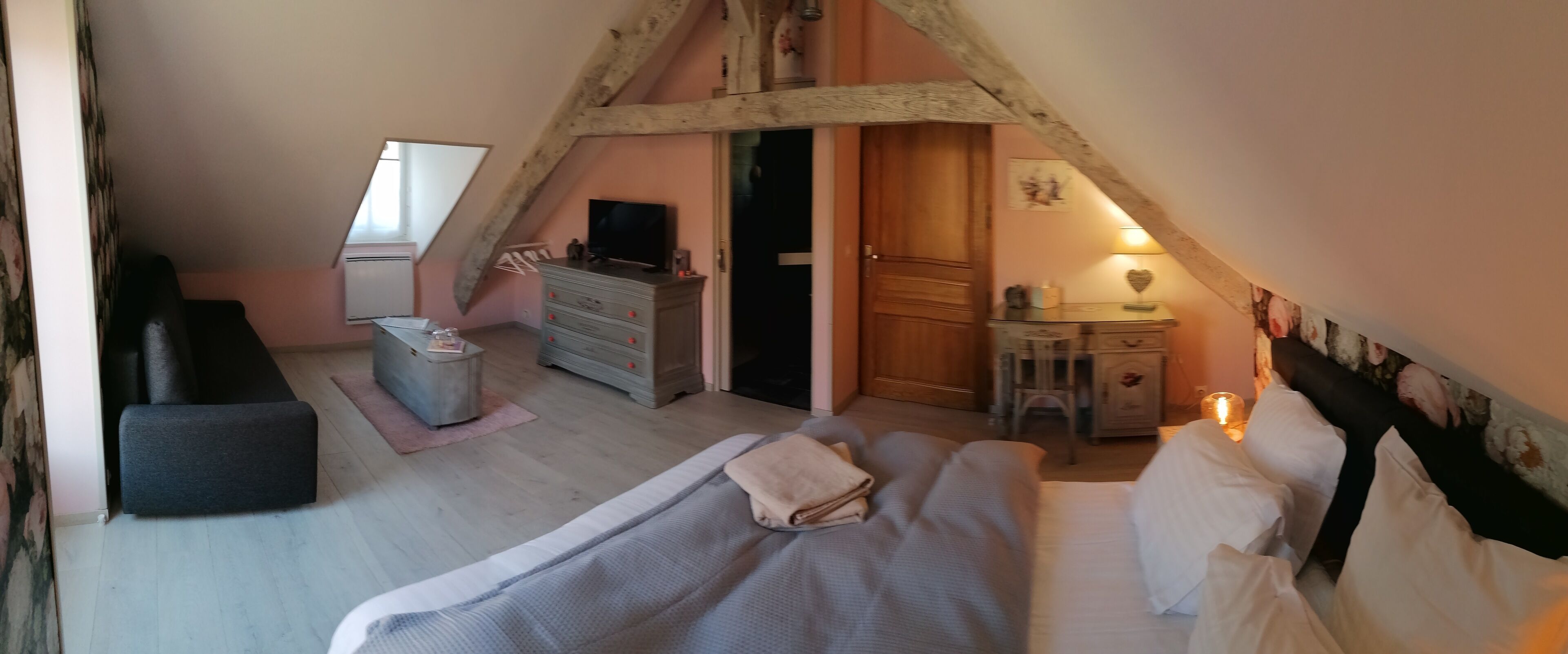 Un dormitorio con cama, cómoda, tocador, televisor y un pequeño escritorio.