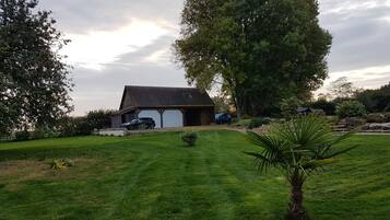 Uma casa com garagem, rodeada por um gramado bem cuidado e árvores.