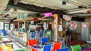 A restaurant with colorful chairs, a bar area, and a wooden wall with a Sinclair sign.