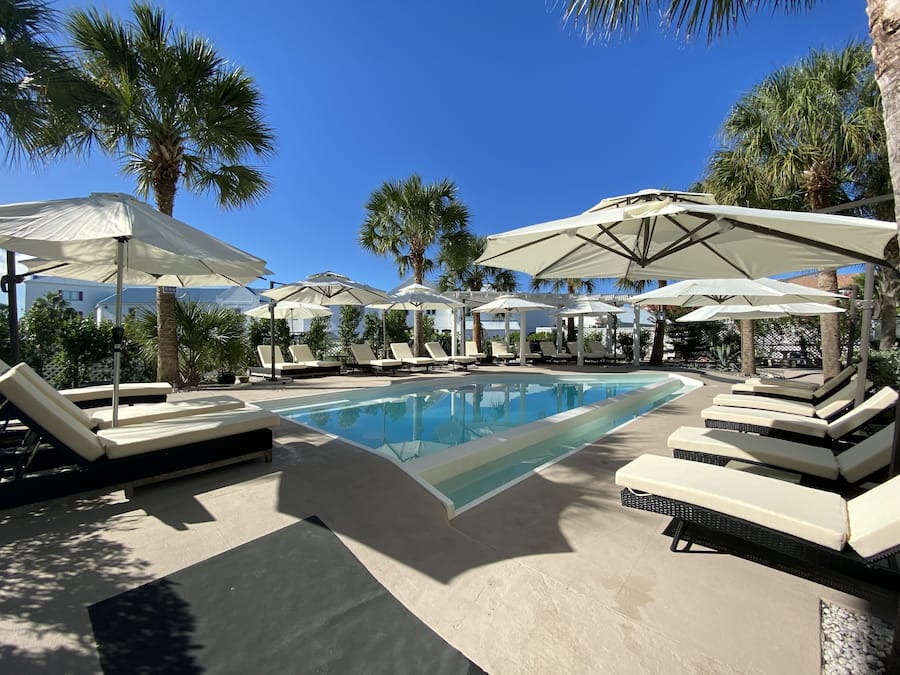 Un área de piscina con sillones de descanso y sombrillas.