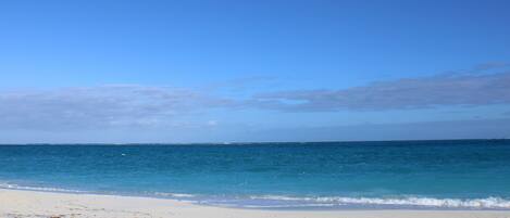 A beach with clear blue water and a sandy shore.